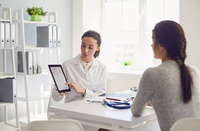 Doctor reviewing a tablet with a patient in a medical office setting.
