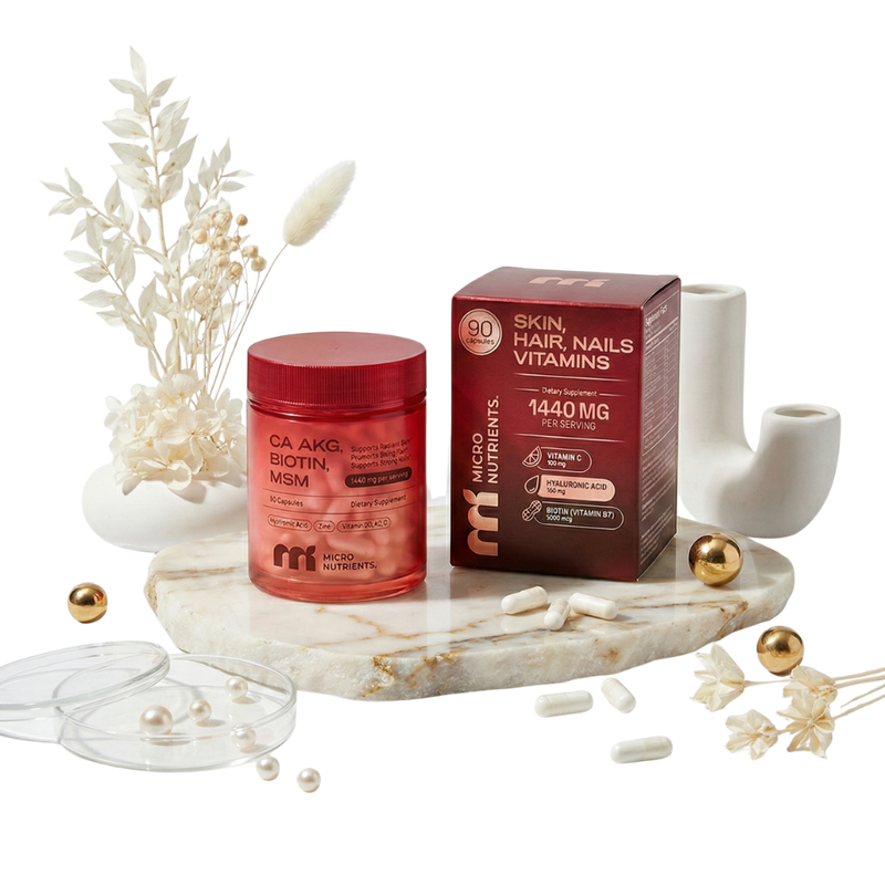 Ca-AKG beauty complex jar and box of skin, hair, and nail vitamins on a marble tray with decorative elements.