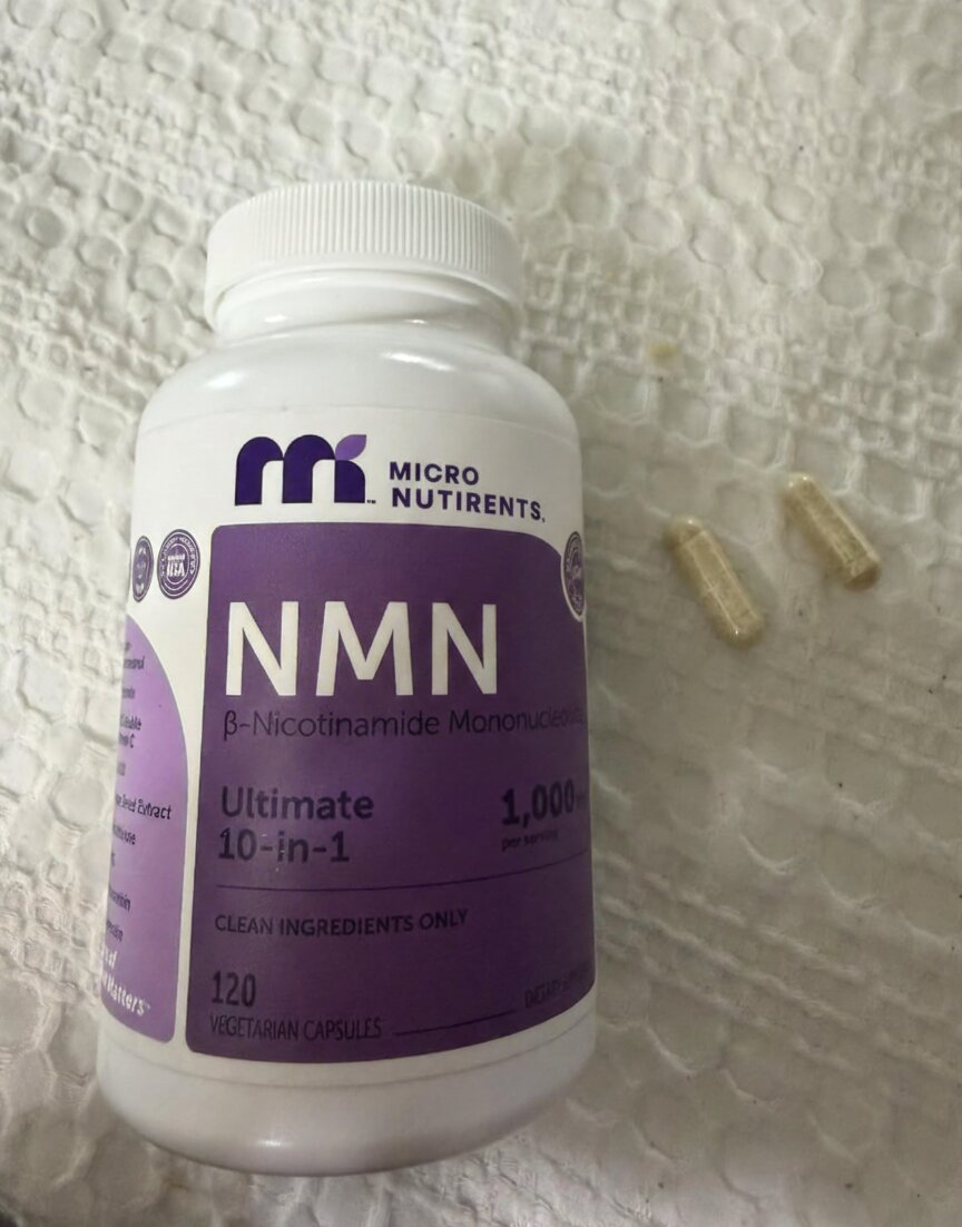 NMN supplement bottle with capsules on a textured surface
