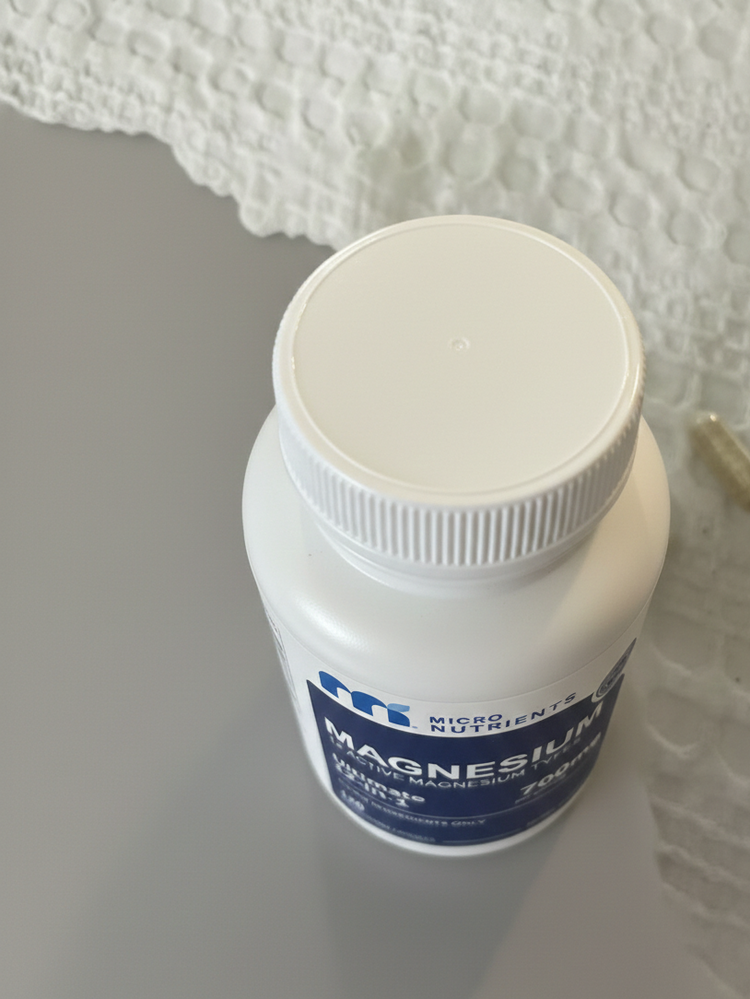 Bottle of Magnesium supplement on a white surface with a textured white background