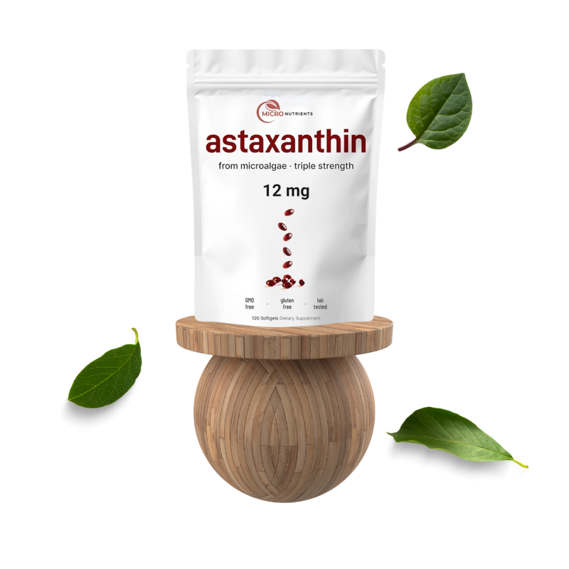 Package of astaxanthin supplement on a wooden stand with green leaves around
