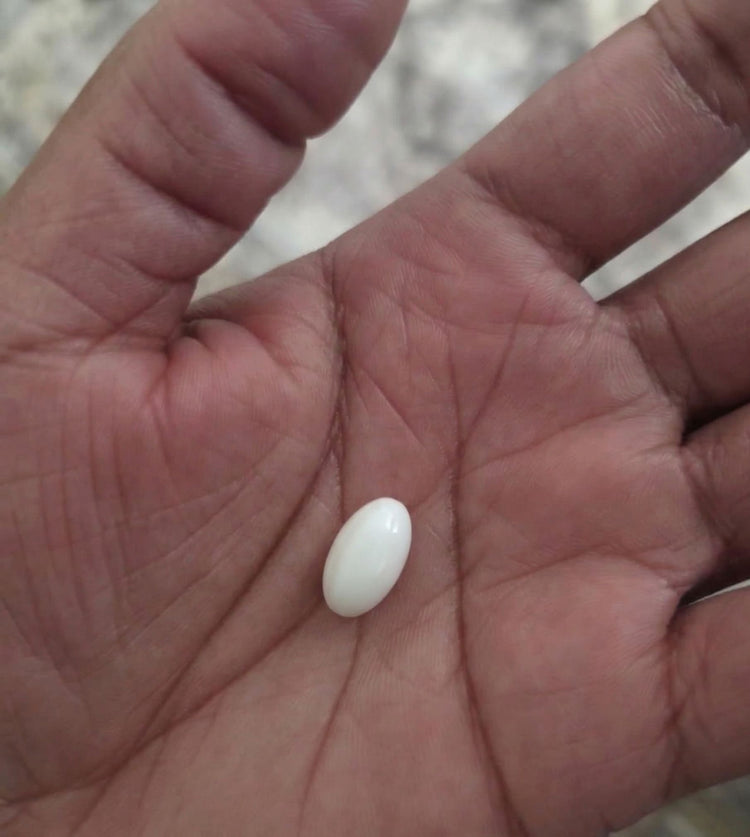 White pill on a person's palm with a blurred background