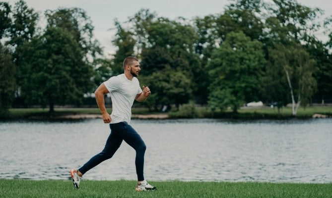 Man running by a lake with trees in the background