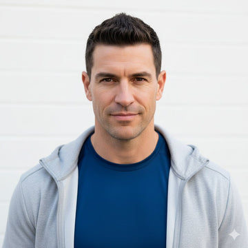 Man wearing a gray hoodie over a blue shirt against a white background