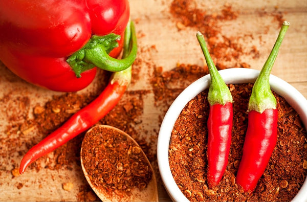 Red peppers and red chilies on a wooden surface with spices.